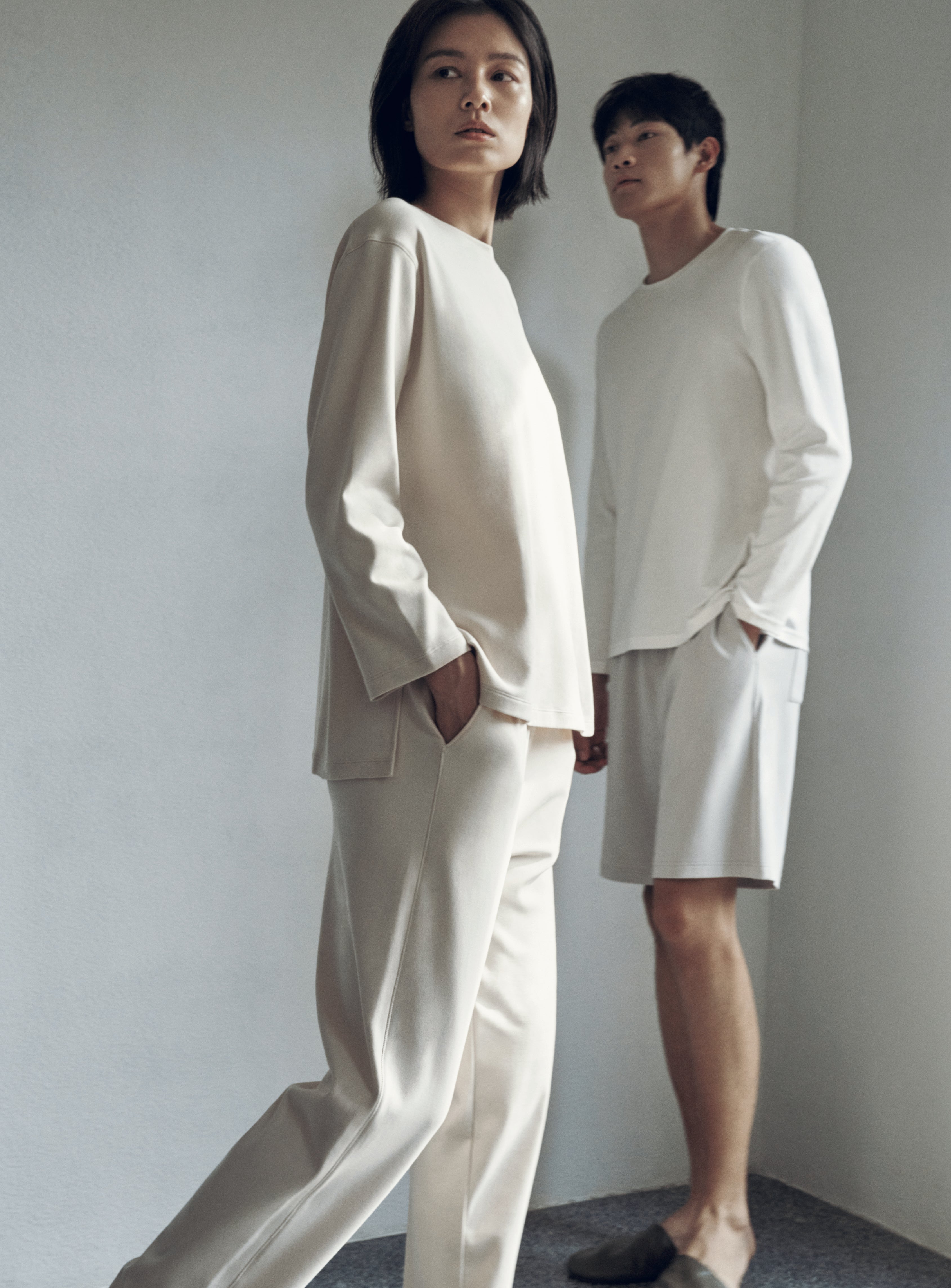 woman with cream color pull over top and pants, a man with white t-shirt and shorts
