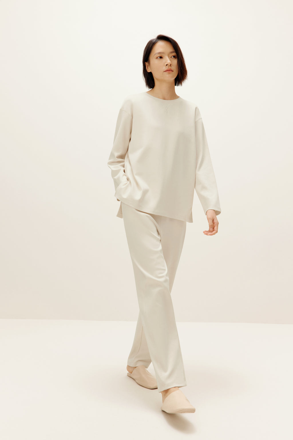 a woman wearing a cream color pull over top and pants
