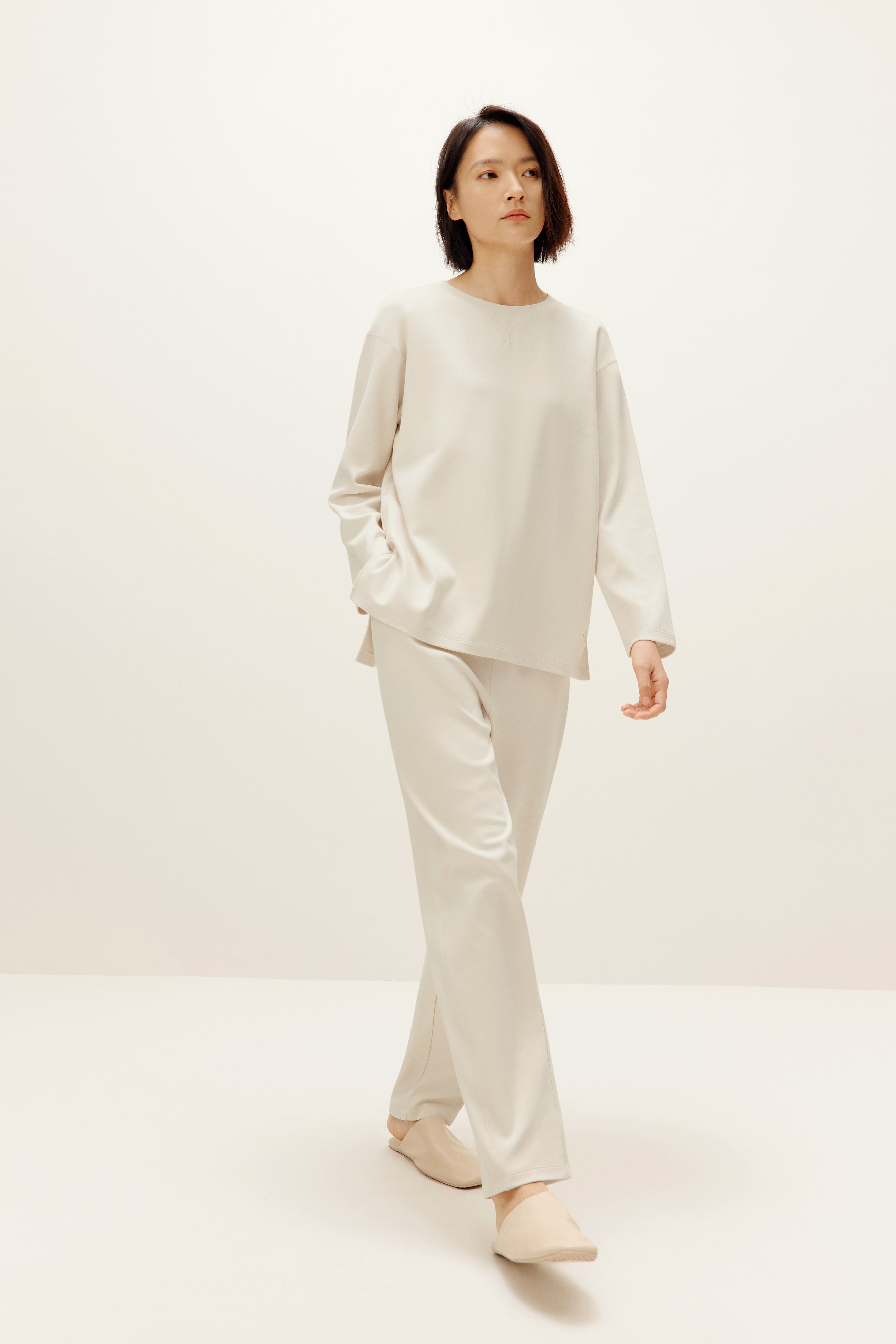a woman wearing a cream color pull over top and pants