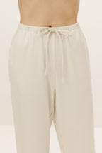 a close look of the waist of a pair of cream color pants with drawstring 