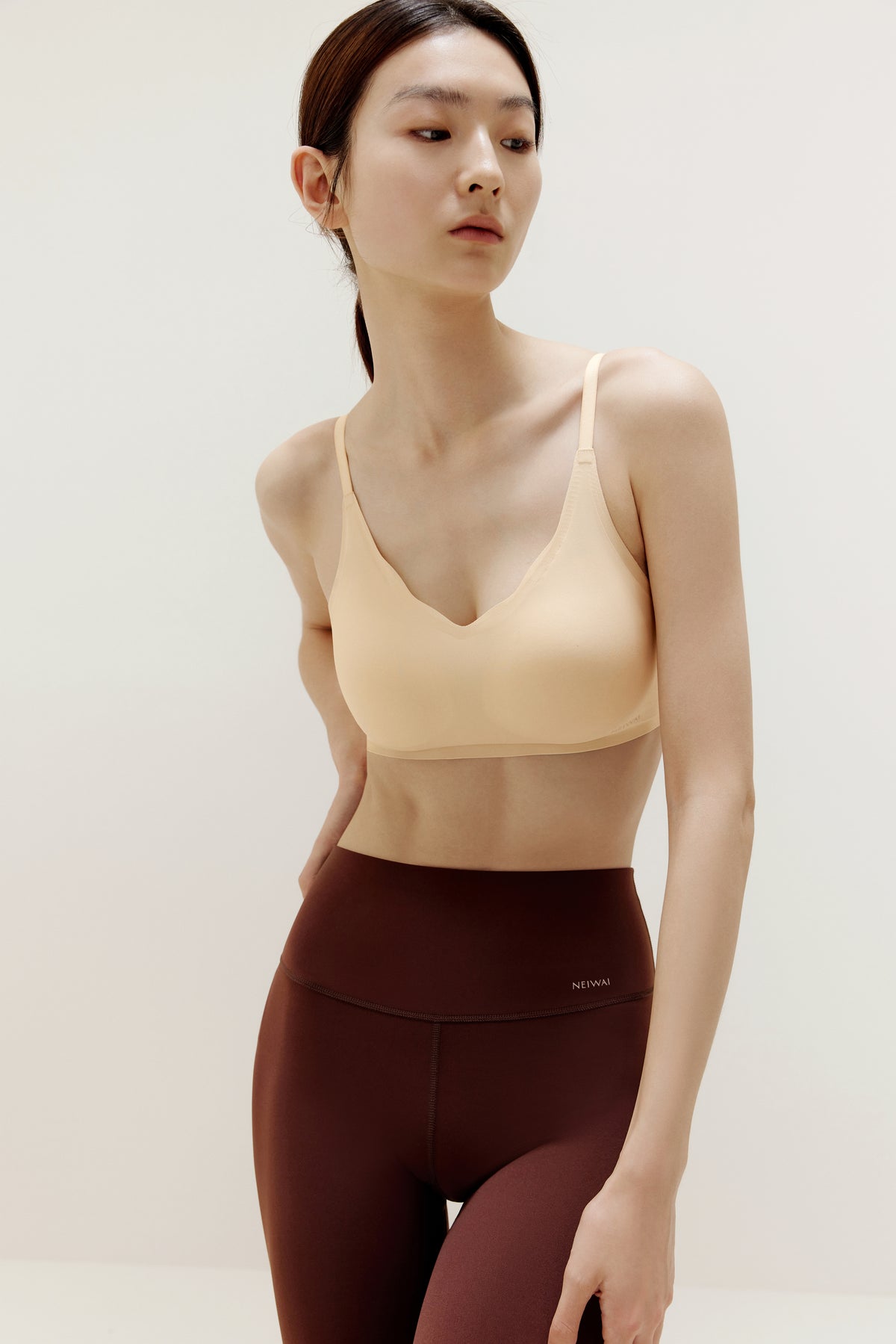 Woman wearing beige bra and maroon leggings