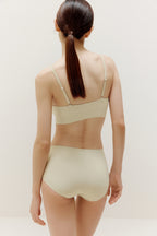 a woman wearing a set of cream color underwear  from back view