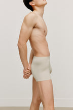 side of a man wearing a cream brief