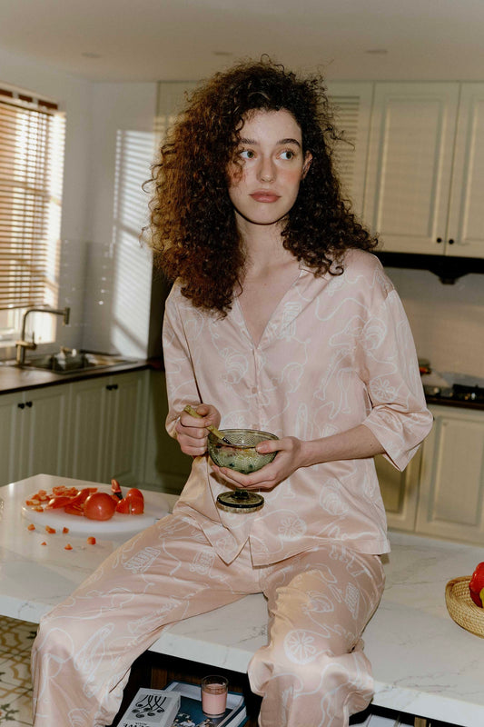 woman with pink pajama shirt with white sketches and matching pants