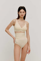 woman in cream color cross over bra and high waist brief