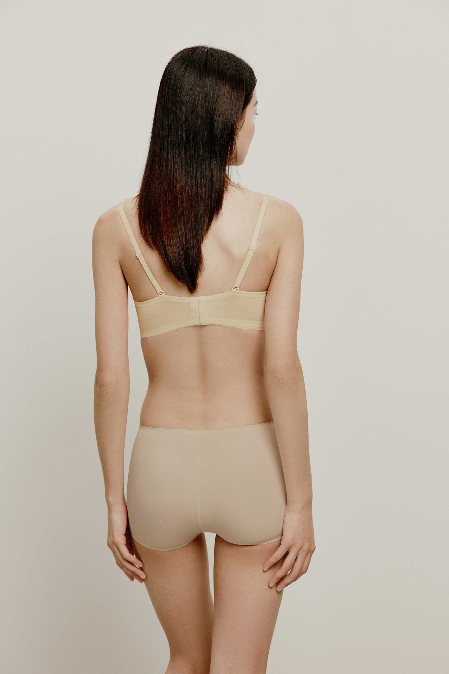 back of woman in cream color bra and nude brief