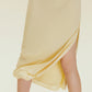 Close up of skirt of cream-colored dress with side slit