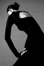 back of woman in black long sleeve top and midi skirt